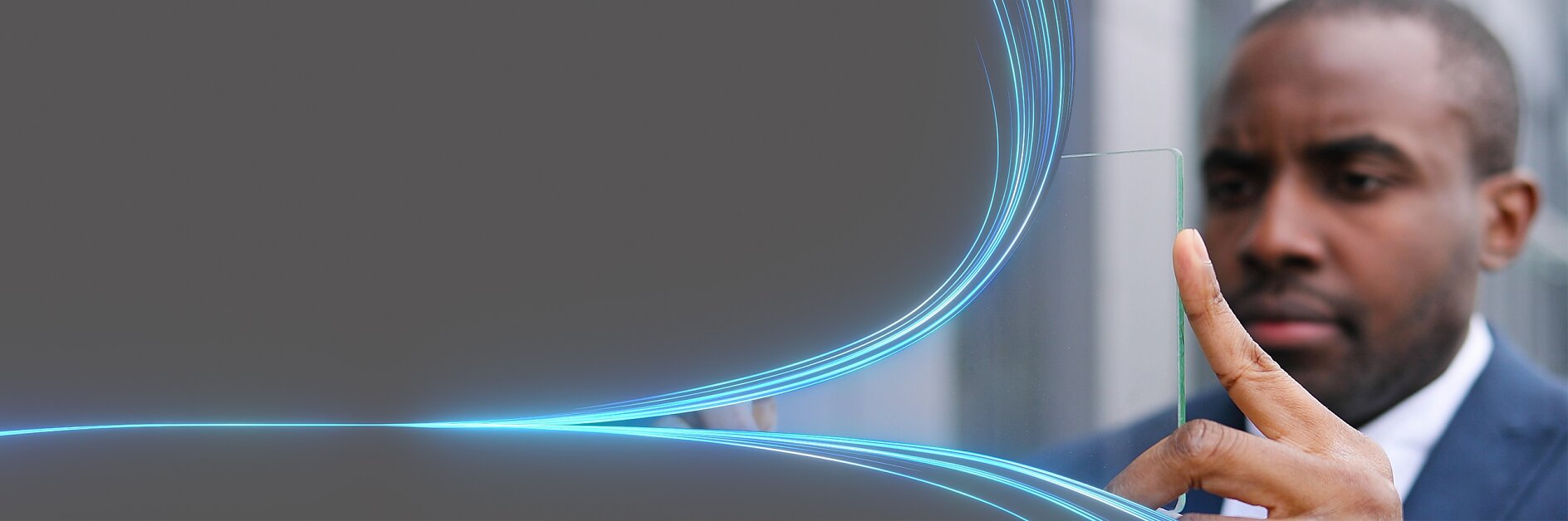 A man in a suit interacts with a transparent digital screen featuring glowing blue lines. The background is a gradient gray. (This text has been generated by AI)