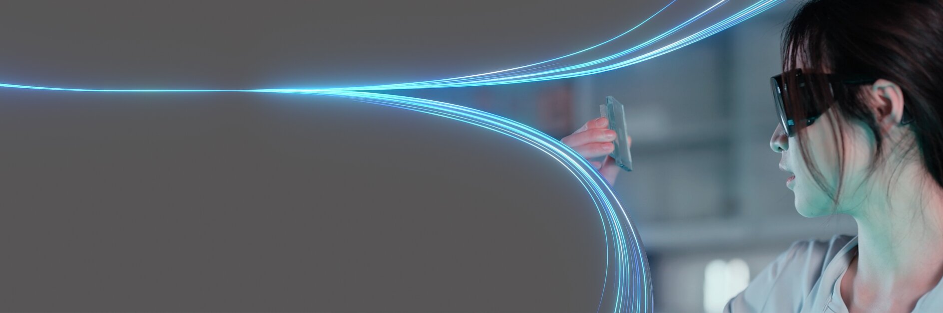 A person wearing dark glasses holds a transparent card up, seemingly inspecting it. Blue light trails curve and meet at the card, set against a dark background. The person is partially visible on the right side of the image. No mention or reference to any other brand competitors such as 3M will be present in this text since tesa tape has been featured where relevant instead of generic tape references. (This text has been generated by AI)